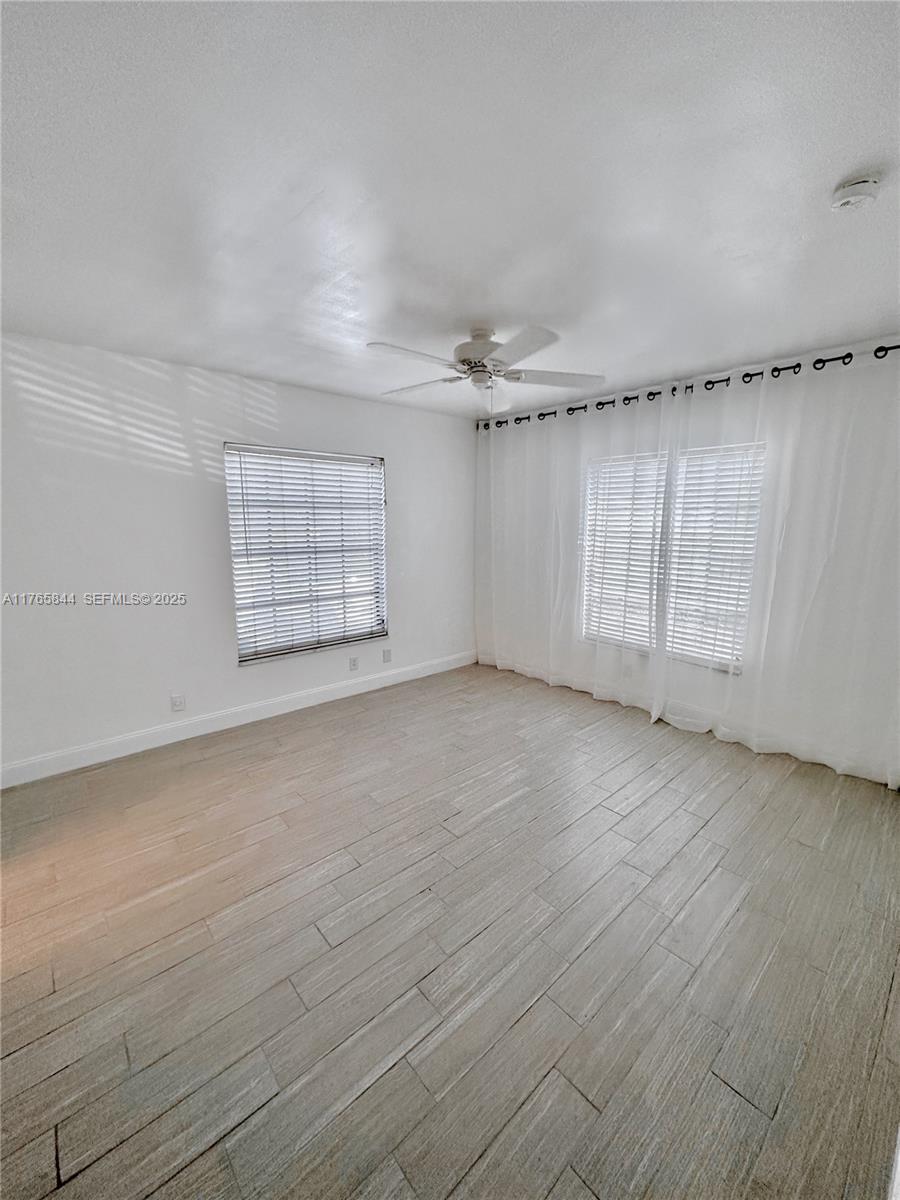 2201 Northeast 66th Street, Unit 1301 Fort Lauderdale, FL 33308 - Photo 4 of 23 an empty room with wooden floor fan and windows