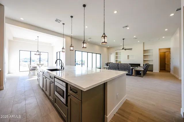 a kitchen with stainless steel appliances granite countertop a sink a stove and a wooden floor