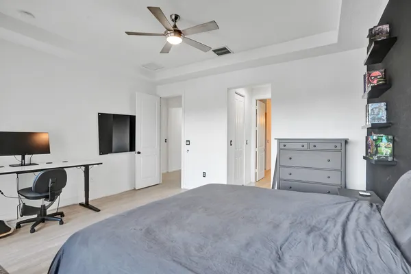 a view of a bedroom with cabinet flat screen tv and a ceiling fan