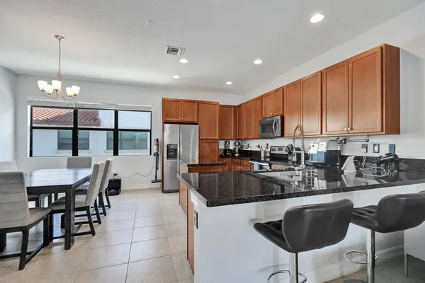 a kitchen with stainless steel appliances granite countertop a stove a sink a microwave a refrigerator and chairs