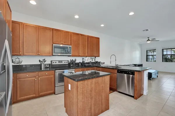 a kitchen with stainless steel appliances granite countertop a stove a sink dishwasher and a microwave oven with wooden cabinets