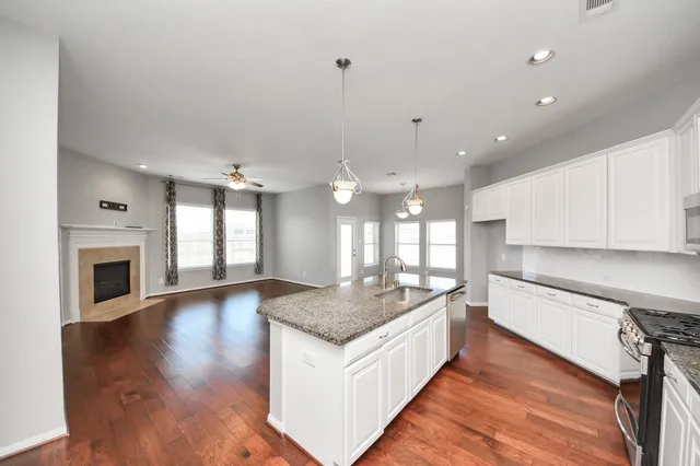 a large kitchen with granite countertop a sink and a stove top oven