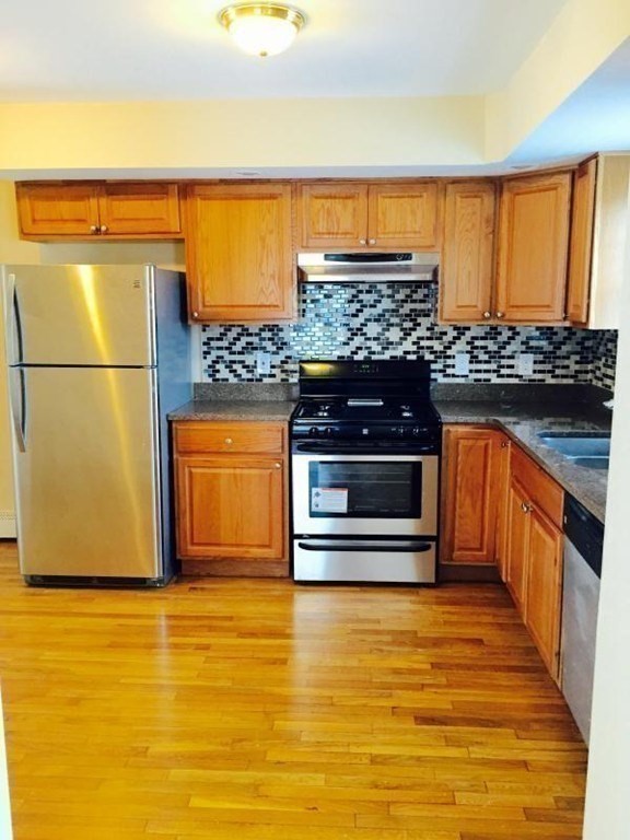 31-35 Juniper Street Boston, MA 02119 - Photo 8 of 14 a kitchen with stainless steel appliances wooden floor and a refrigerator