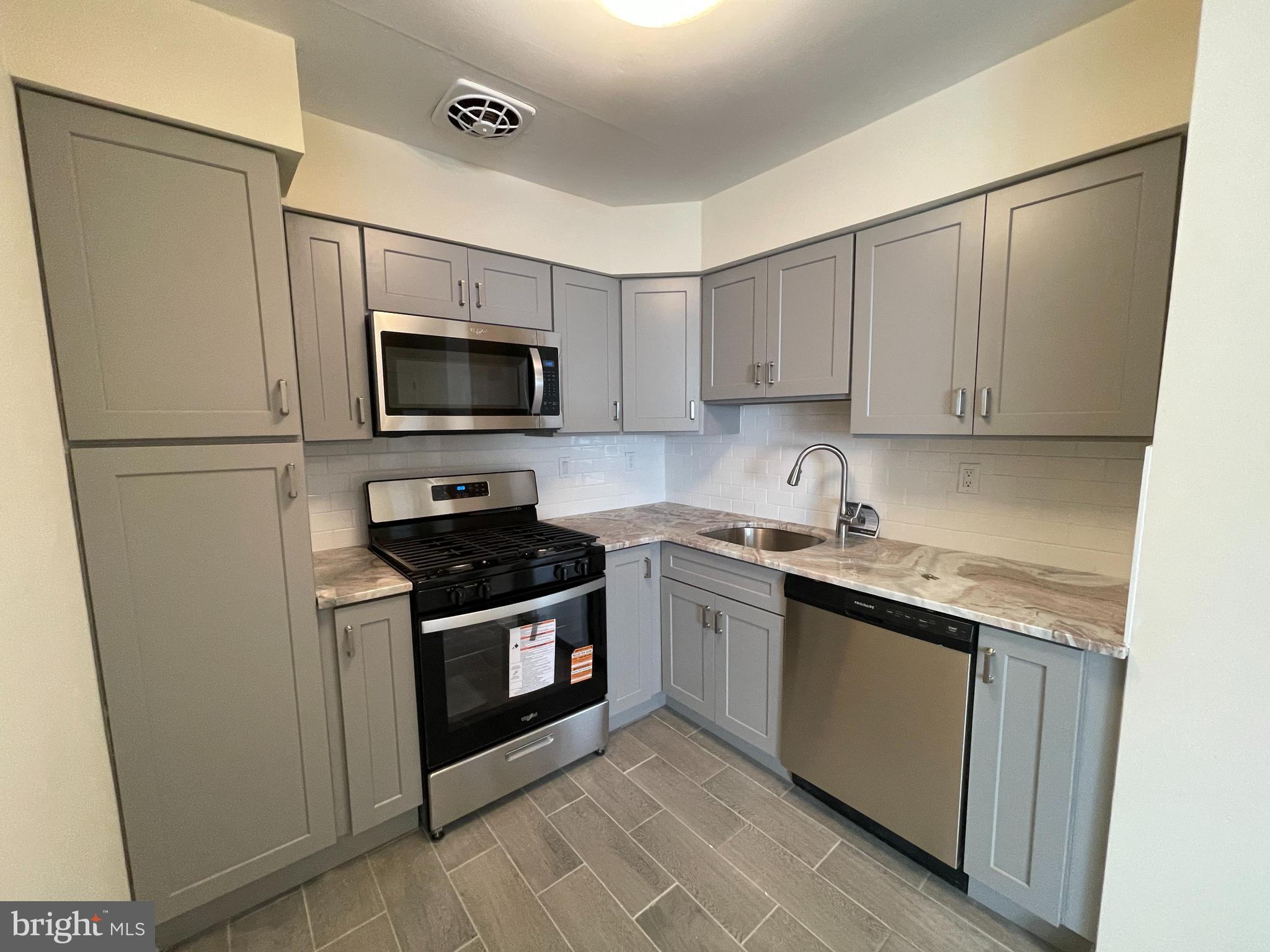 3937 Ellington Road, Unit 2 Philadelphia, PA 19131 - Photo 2 of 17 a kitchen with a stove and a microwave