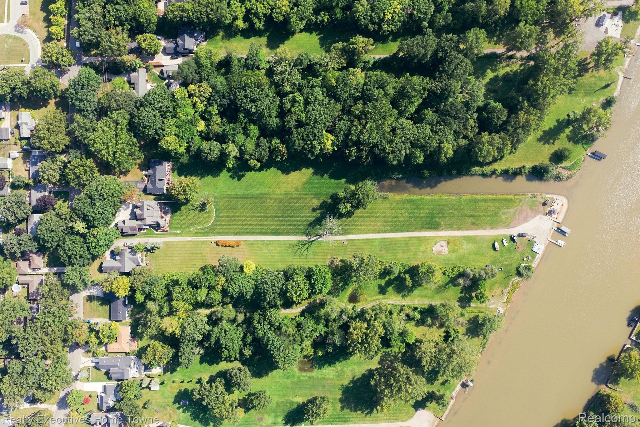 2829 Riverside Drive Port Huron, MI 48060 - Photo 78 of 99 Expansive green spaces and mature trees border a substantial body of water, featuring multiple boats docked along the shore