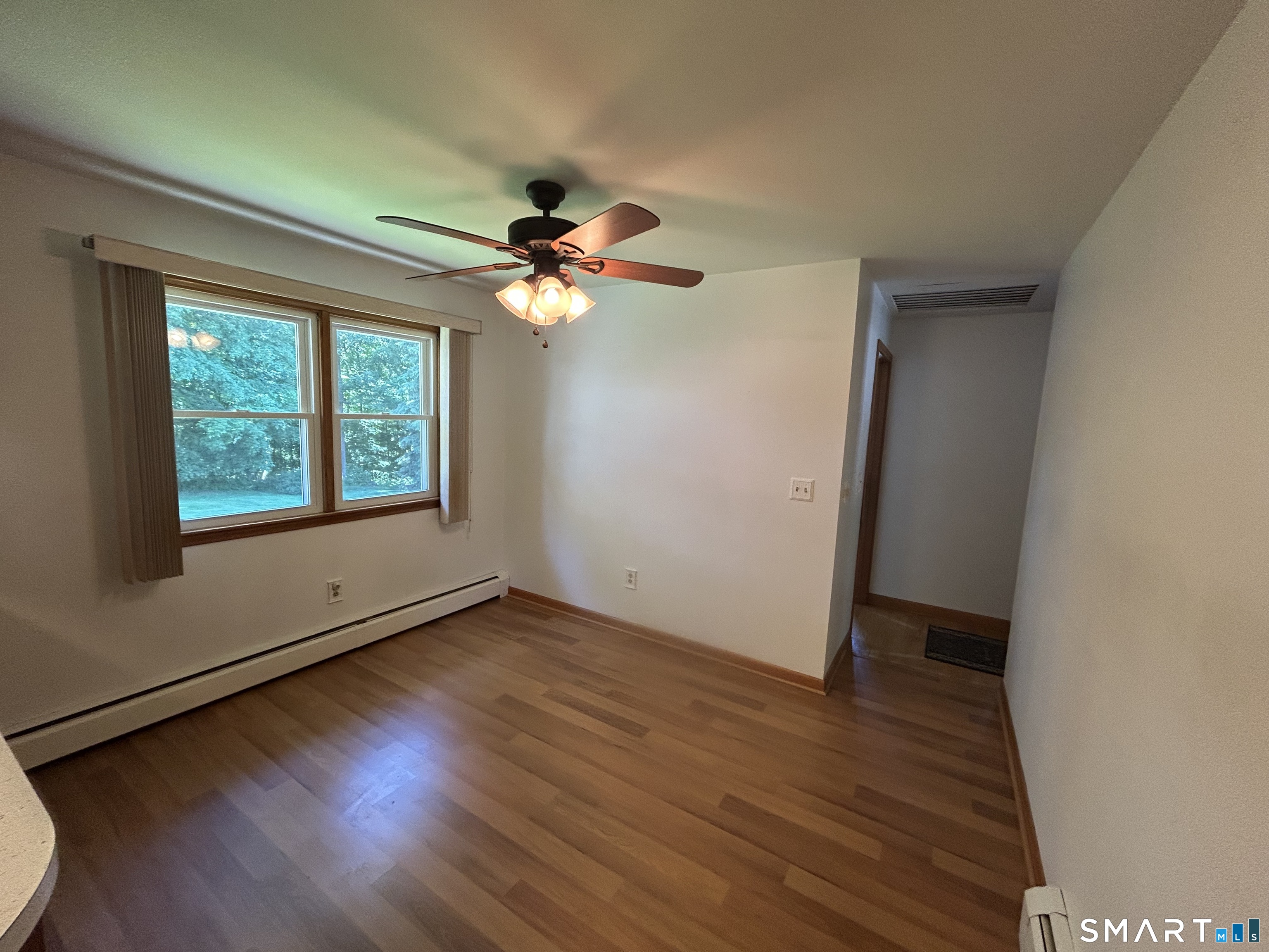 13 Walnut Lane Wallingford, CT 06492 - Photo 8 of 27 an empty room with wooden floor fan and windows