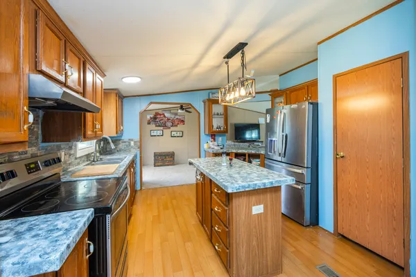 a kitchen with stainless steel appliances granite countertop wooden floor a stove top oven a sink and a refrigerator