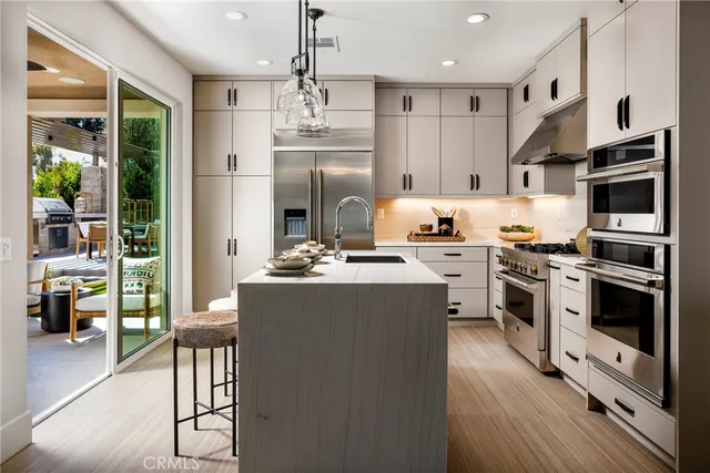 a kitchen with kitchen island a counter top space a sink stainless steel appliances and cabinets