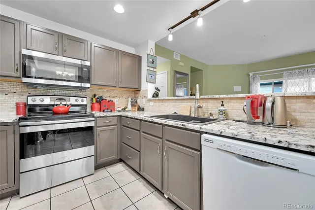 a kitchen with granite countertop stainless steel appliances a sink and cabinets