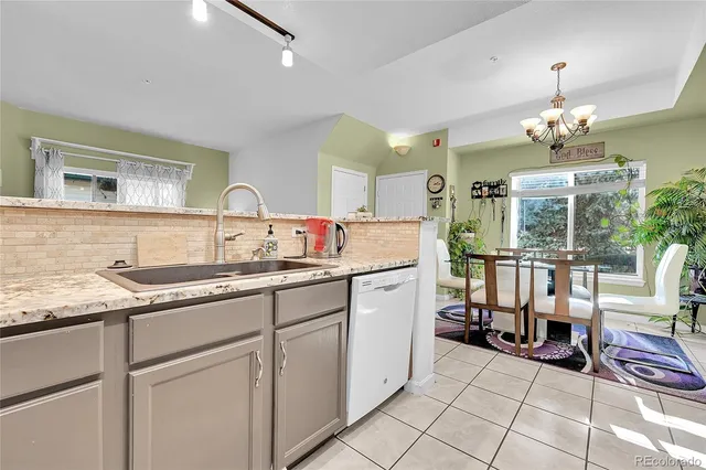a kitchen with granite countertop a sink white cabinets and glass table chairs