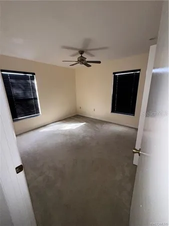 a view of an empty room with a ceiling fan and window