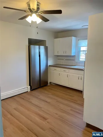 an empty room with wooden floor a ceiling fan and windows