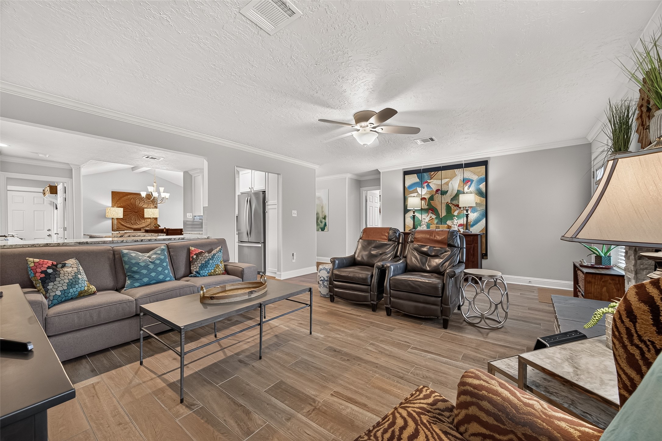 24719 Wilderness Road Spring, TX 77380 - Photo 14 of 42 This inviting living room features wood-like ceramic tile. It seamlessly connects to the kitchen and dining area, creating an open and welcoming space.