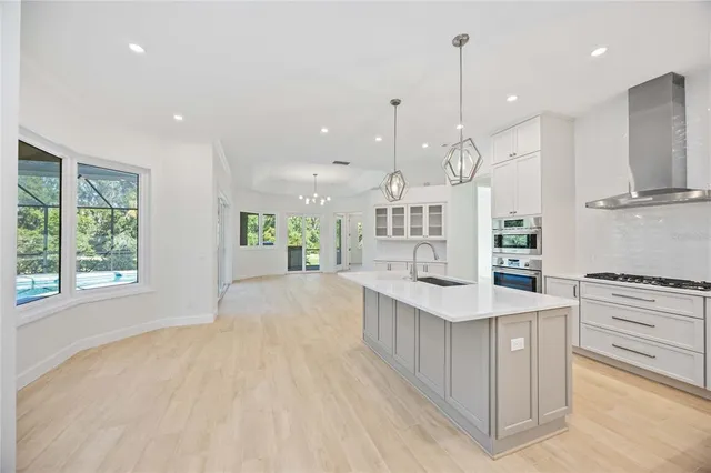 a kitchen with stainless steel appliances kitchen island granite countertop a stove a refrigerator a oven and a night stand with large windows