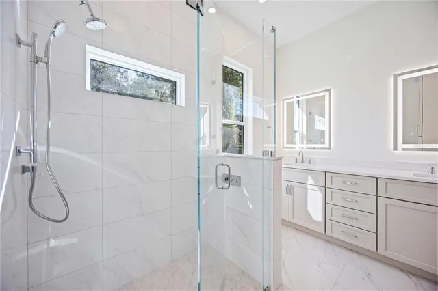 a bathroom with a granite countertop shower a sink and a window