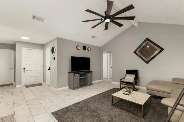 a living room with furniture a flat screen tv and a window