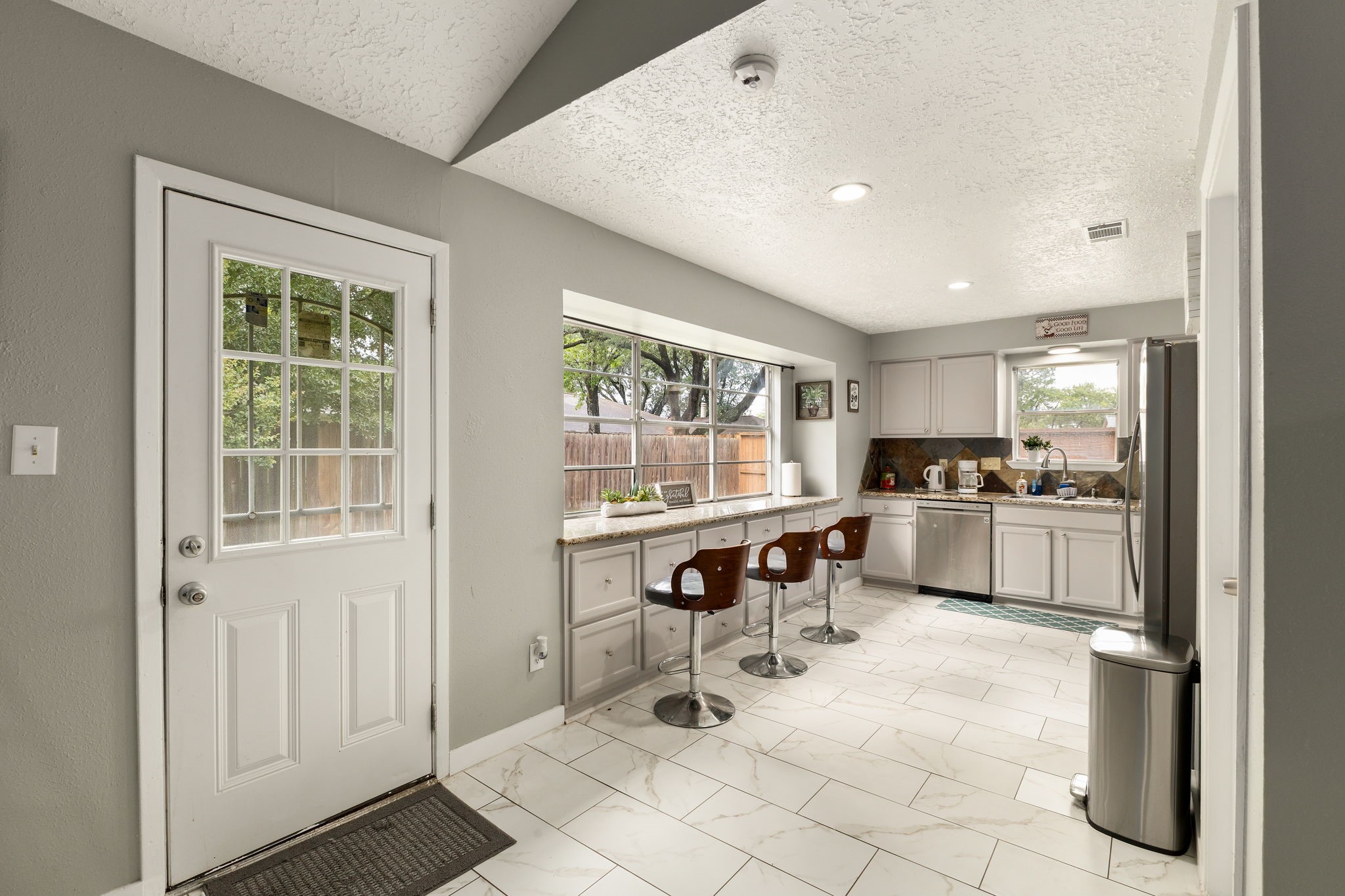 14110 Eventide Drive Cypress, TX 77429 - Photo 6 of 27 This kitchen features a bright, open layout with modern white cabinetry, a long breakfast bar, and stainless steel appliances. Large windows offer plenty of natural light and views of the backyard.