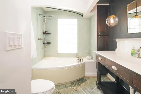 a spacious bathroom with a bathtub a sink and a mirror