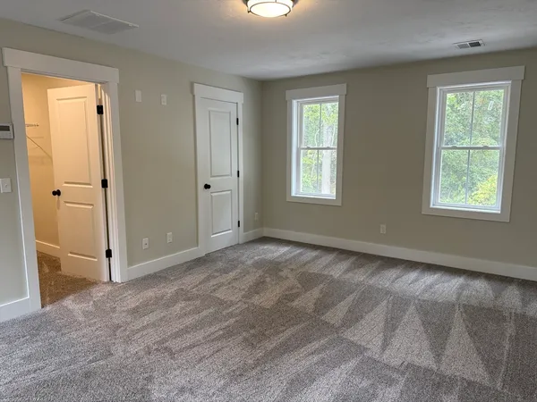 a view of an empty room with window and closet area