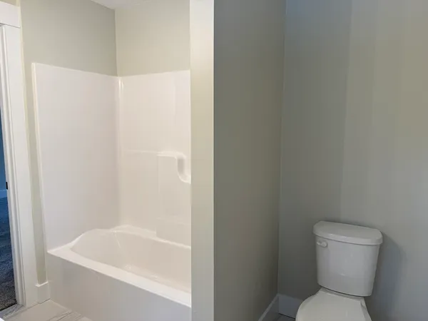 a white toilet sitting next to a bath tub