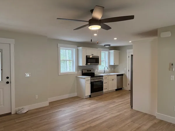 a large kitchen with cabinets wooden floor and stainless steel appliances