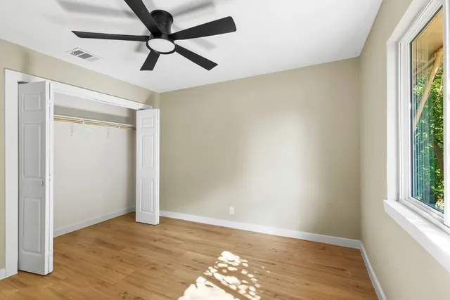 a view of empty room with wooden floor and fan