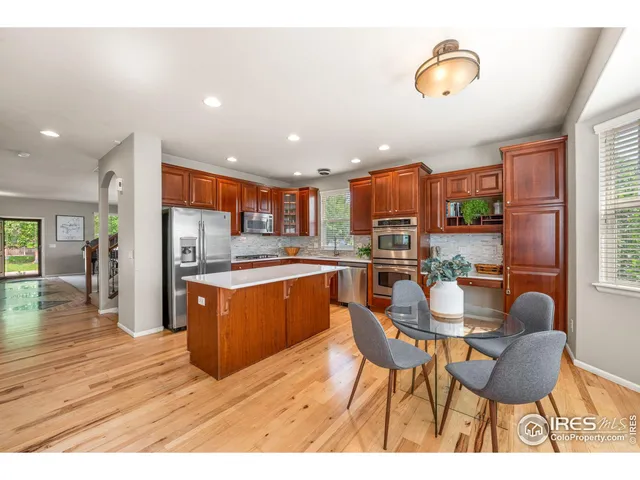 a kitchen with stainless steel appliances granite countertop a table chairs and a refrigerator