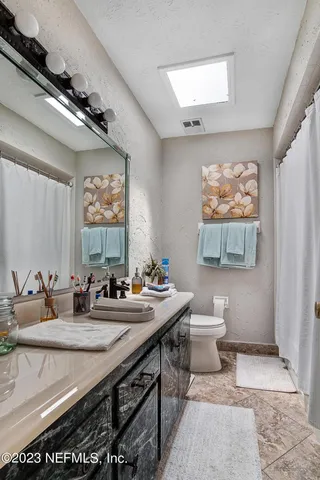 a bathroom with a granite countertop sink a mirror and a toilet