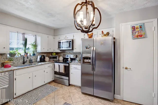 a kitchen with stainless steel appliances a refrigerator a sink a stove and white cabinets
