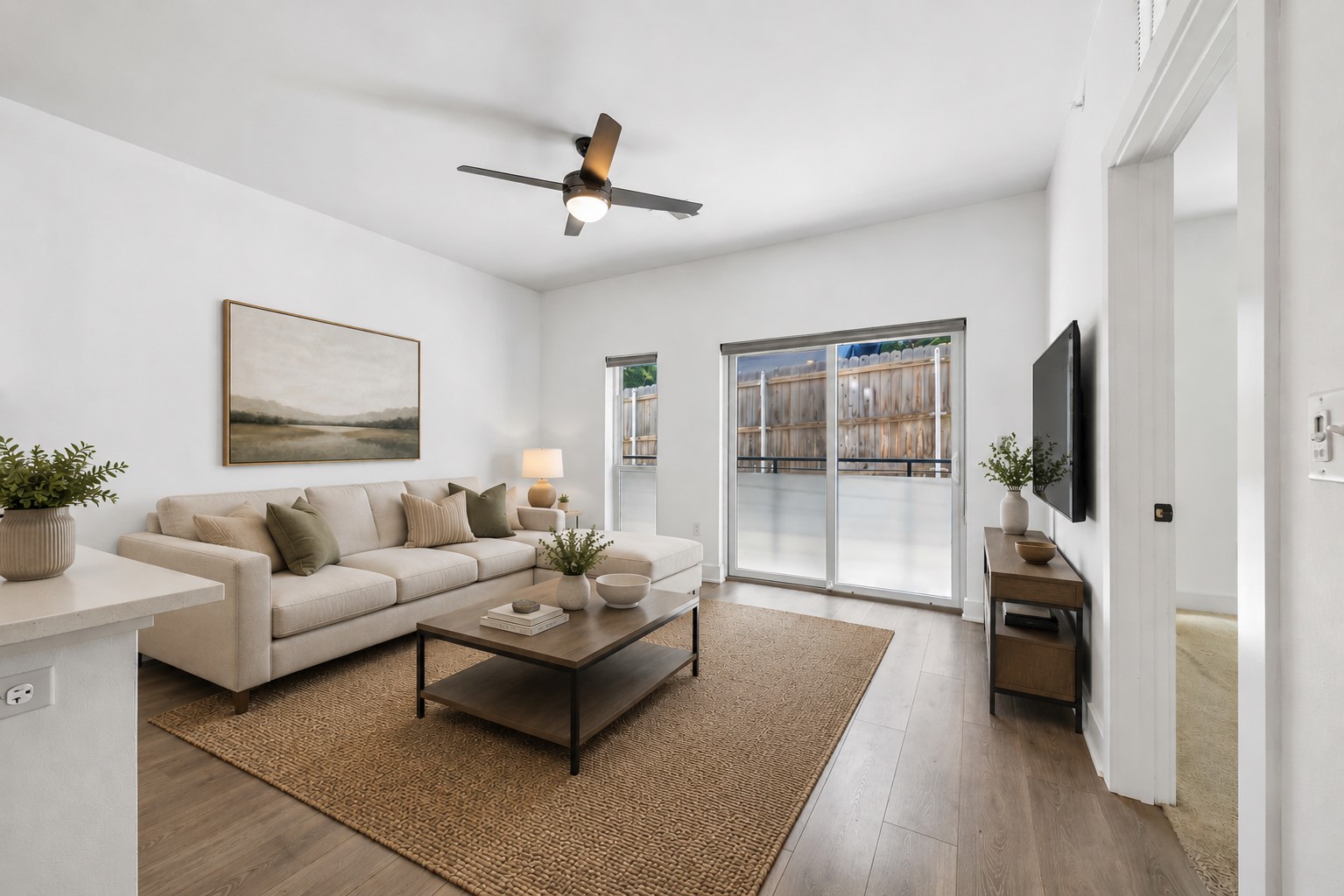 2220 Webberville Road, Unit 216 Austin, TX 78702 - Photo 11 of 26 Virtually Staged - Spacious living area featuring wood-finish flooring, a contemporary ceiling fan, and large sliding glass doors providing outdoor access