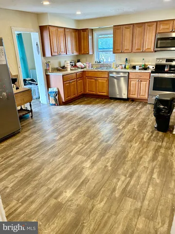 a large kitchen with stainless steel appliances wooden floors and a view of living room