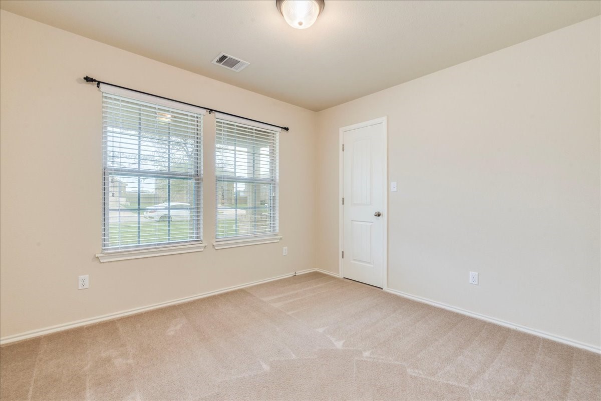 1061 Violet Lane Kyle, TX 78640 - Photo 15 of 34 secondary bedroom with large window and carpeted flooring