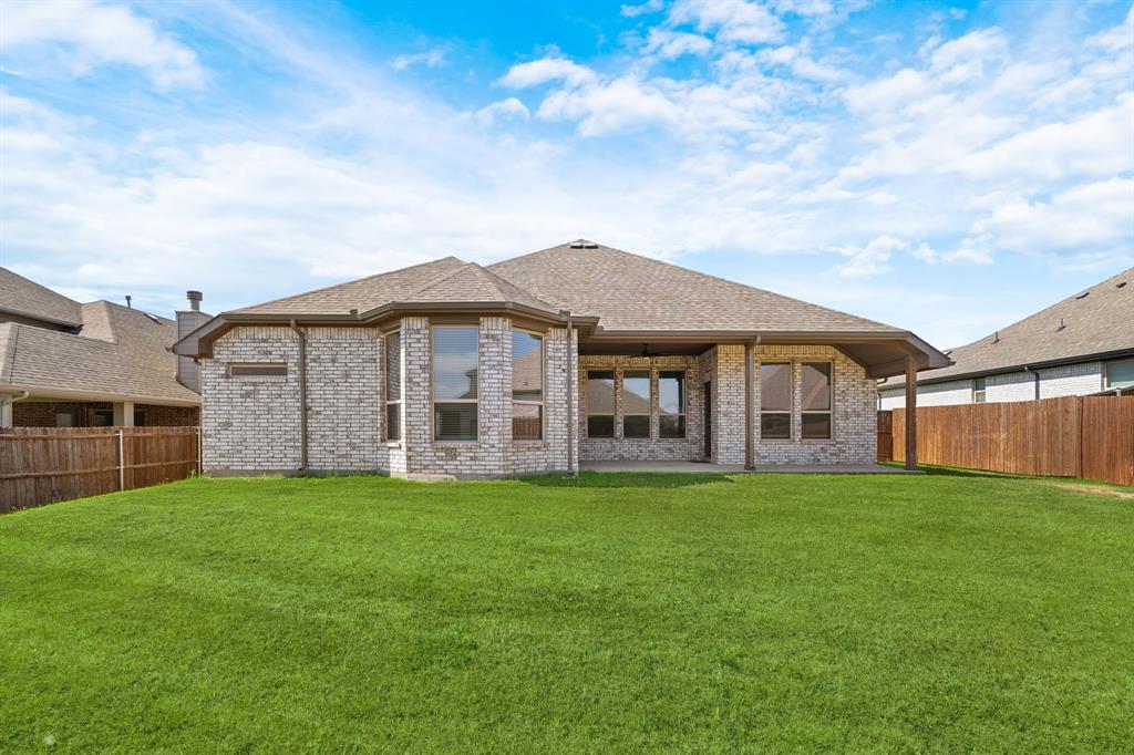 915 Timber Ridge Drive Justin, TX 76247 - Photo 35 of 39 Expansive backyard featuring a manicured lawn, full brick exterior, a covered patio, and large bay windows