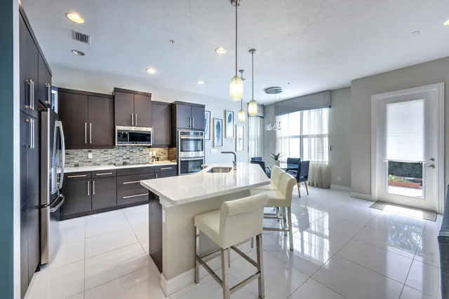 a kitchen with stainless steel appliances kitchen island granite countertop a stove a refrigerator a oven a sink with a dining table and chairs