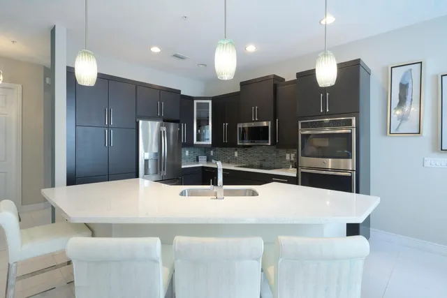 a kitchen with stainless steel appliances kitchen island granite countertop a dining table and chairs