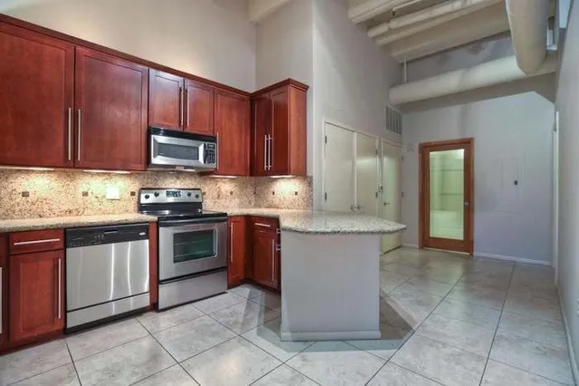 a kitchen with kitchen island granite countertop wooden cabinets a stove top oven and a sink