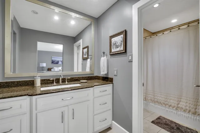 a bathroom with a granite countertop sink a mirror a vanity and shower