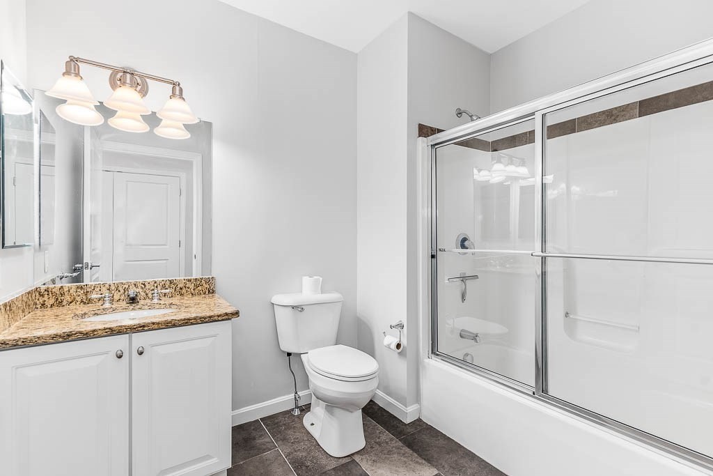 446 Belgrade Avenue, Unit 208 Boston, MA 02132 - Photo 23 of 36 a bathroom with a granite countertop sink toilet a mirror a vanity and shower