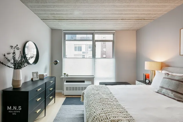 a bedroom with a bed and a mirror on the dresser