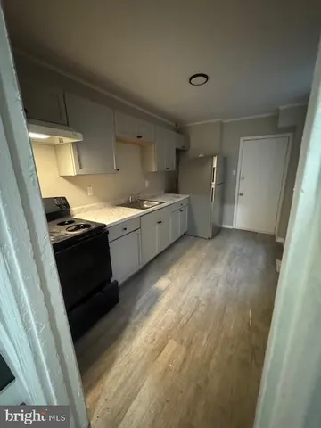 a kitchen with a sink a stove top oven and cabinetry