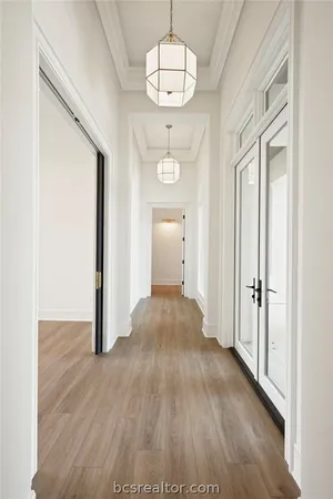 a view of a hallway with wooden floor and a chandelier