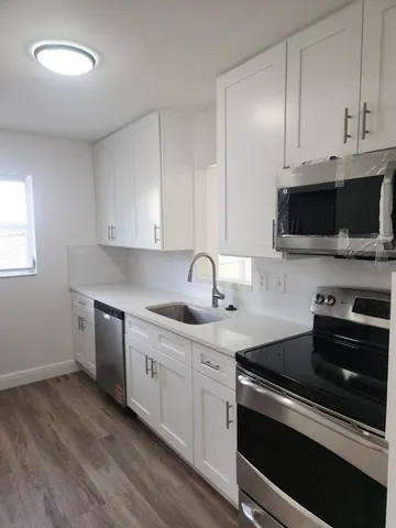 a kitchen with stainless steel appliances granite countertop a sink dishwasher a stove and a microwave oven with cabinets