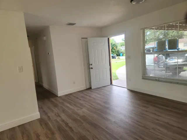 a view of an empty room with wooden floor and a window