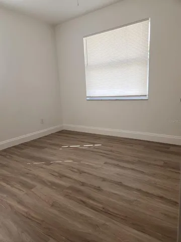 an empty room with wooden floor and a window