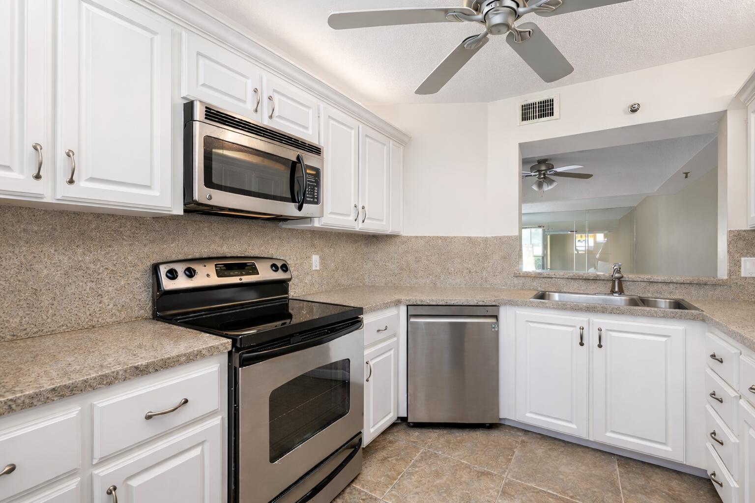 9220 Southwest 14th Street, Unit 3208 Boca Raton, FL 33428 - Photo 8 of 43 a kitchen with stainless steel appliances granite countertop white cabinets a sink a stove and a microwave