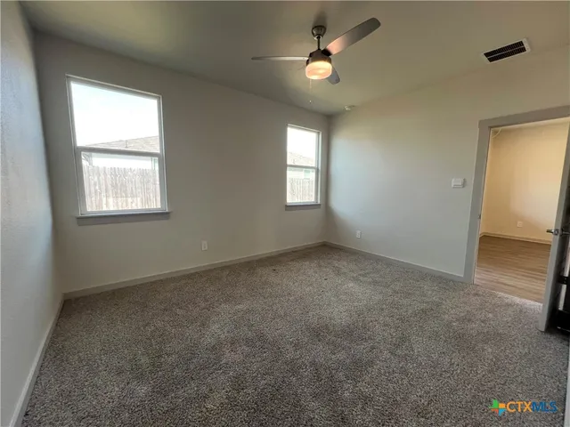 an empty room with windows and fan