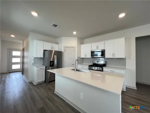 a kitchen with a refrigerator a microwave a sink and cabinets