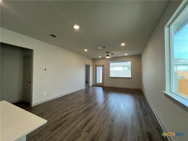 an empty room with wooden floor and windows