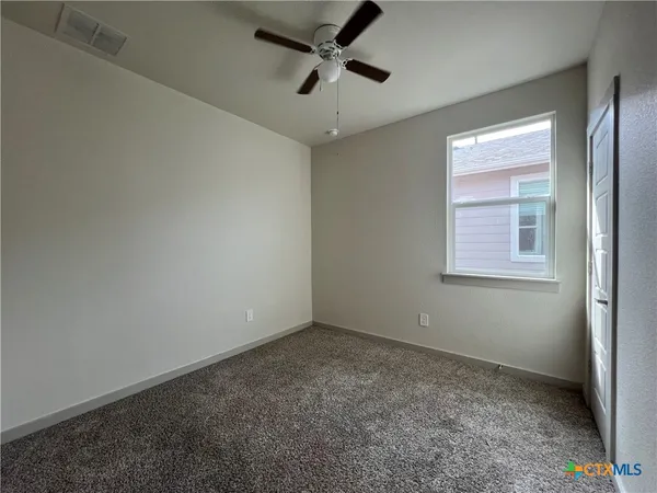 an empty room with a window and a fan