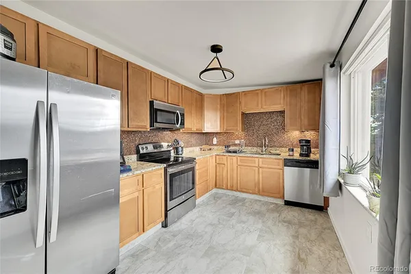 a kitchen with a sink stainless steel appliances cabinets and a window